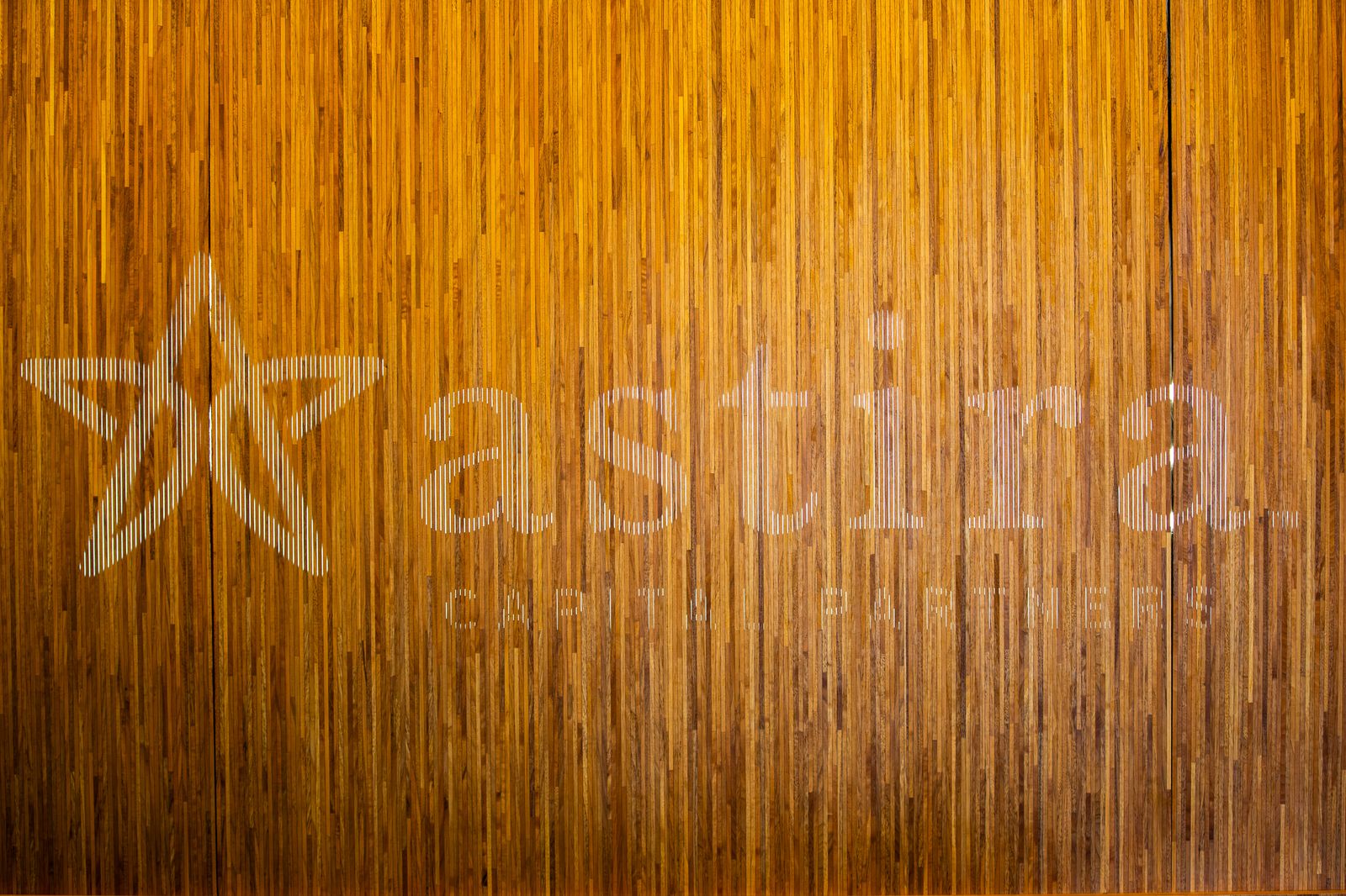 The Astira Capital Partners logo, backlit through the wooden slat wall of the Boston office