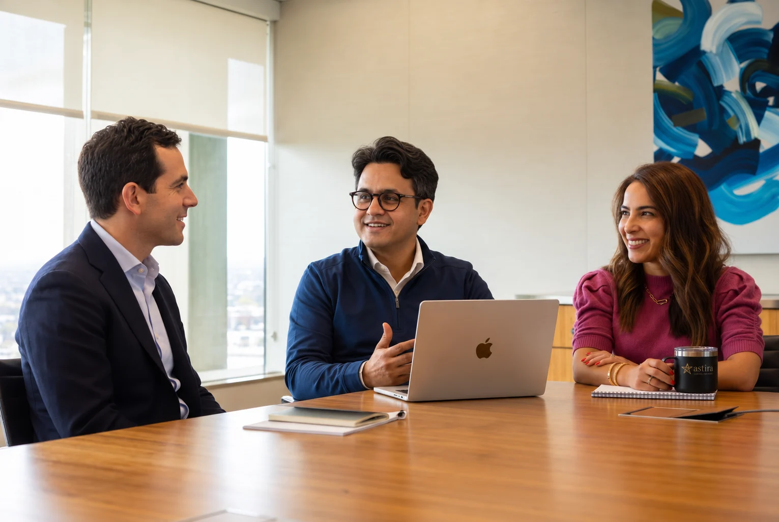 Three Astira colleagues in discussion around a laptop